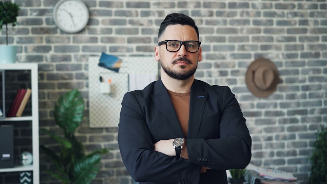 A small-business owner standing in their workspace, arms crossed.